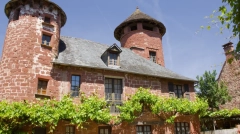 A majestic red sandstone manor with two towers and green vines in Collonges-la-Rouge, France.