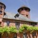 A majestic red sandstone manor with two towers and green vines in Collonges-la-Rouge, France.