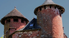 Iconic medieval red sandstone towers with slate roofs under a deep blue sky in Collonges-la-Rouge, France.