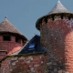 Iconic medieval red sandstone towers with slate roofs under a deep blue sky in Collonges-la-Rouge, France.