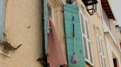 A rustic turquoise wooden shutter with a classic black iron lantern on a warm stucco facade in Tarascon, Provence.