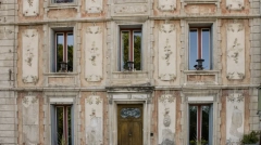 Historic ochre facade with floral frescoes and a carved wooden door in Fontaine-de-Vaucluse.