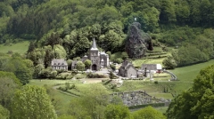 Panoramic view of Saint-Paul-de-Salers, Cantal, France, featuring the iconic volcanic rock and the Virgin Mary statue.