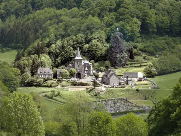 Panoramic view of Saint-Paul-de-Salers, Cantal, France, featuring the iconic volcanic rock and the Virgin Mary statue.