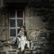 Witch doll sitting on a rustic stone window sill in the medieval village of Salers, France.